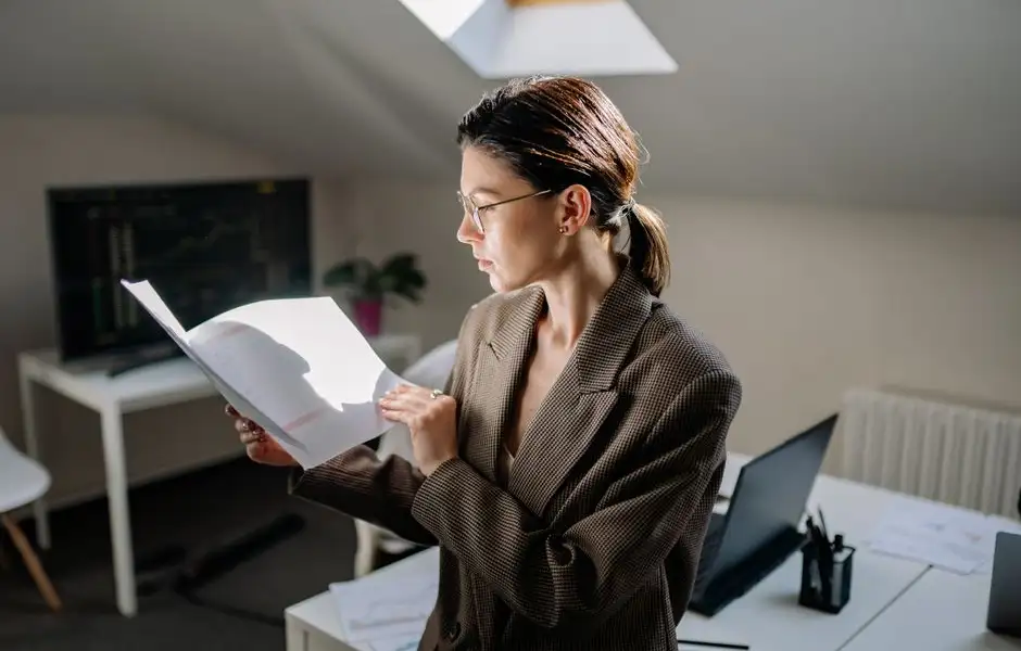 Une personne lit un devis d’assurance à son bureau, surlignant des lignes de garanties et de franchises.